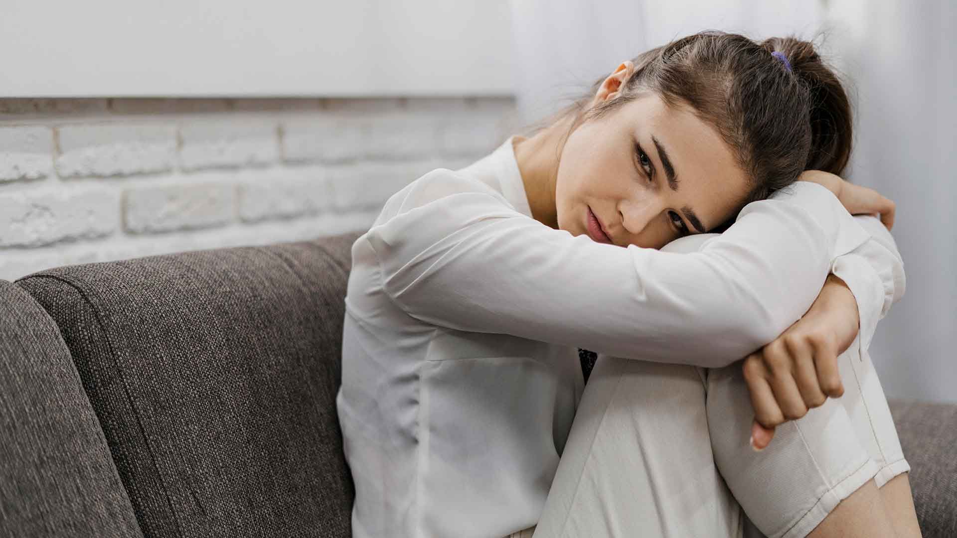 Mujer encogida en sofá