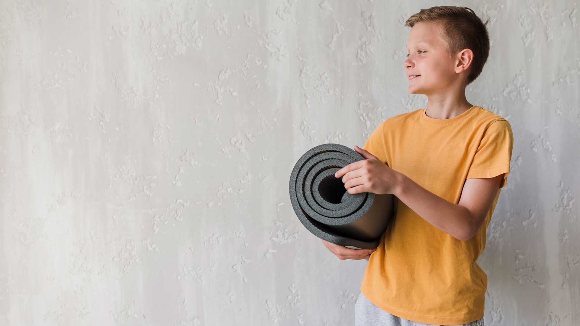 Niño con estera de yoga