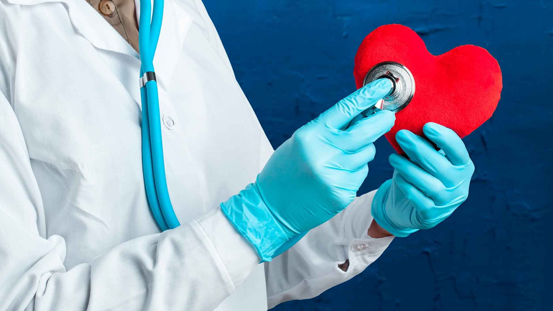 Doctor auscultando un corazón de plástico